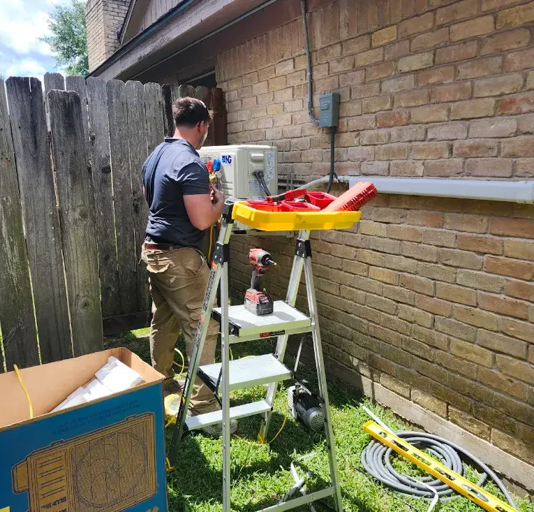 A licensed installer using manifold gauges, a vacuum pump, and power tools to commission a ductless mini split at a Texas home